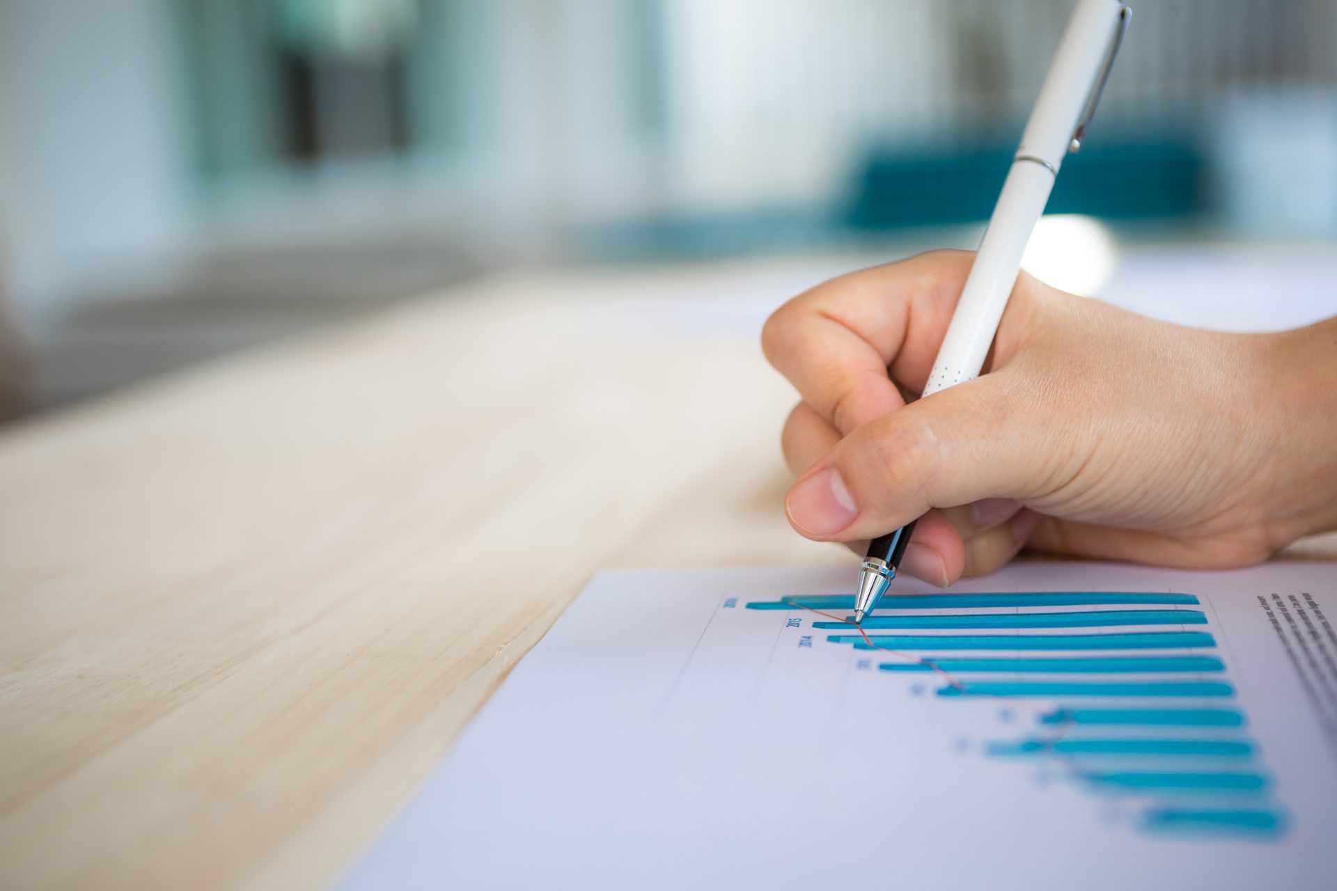 Main tenant un stylo devant un graphique, illustrant les plafonds de chiffre d’affaires de la micro-entreprise